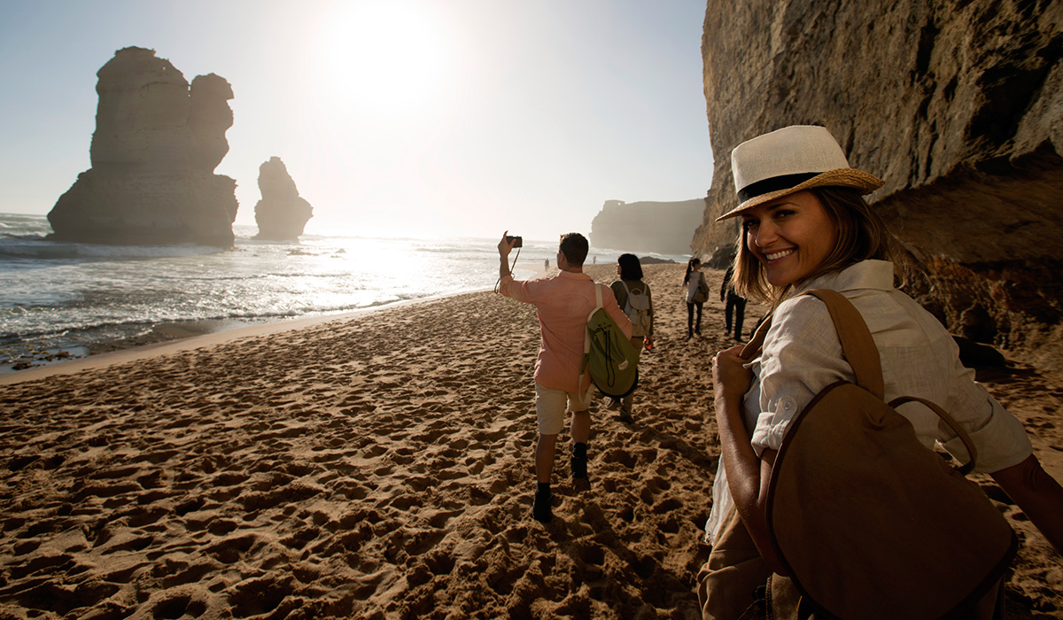 Tourist walking a long a beach with woman looking back smiling